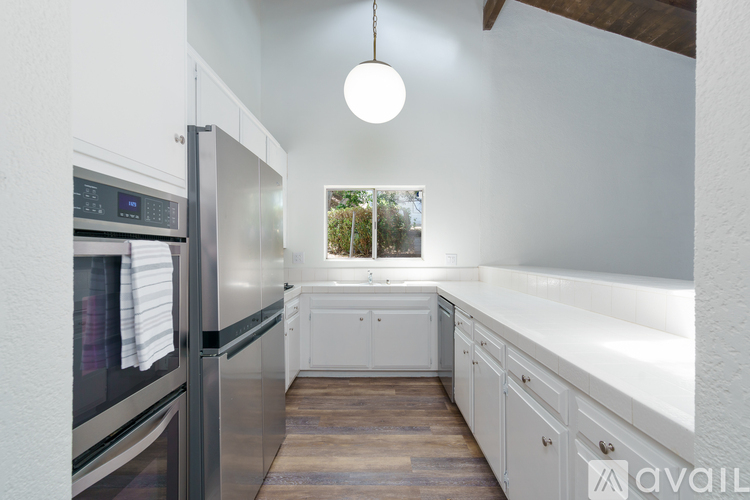 A modern kitchen with white cabinets and a stainless steel refrigerator.
