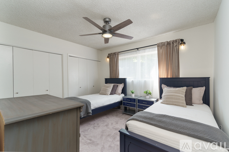 A bedroom with two beds and a ceiling fan.