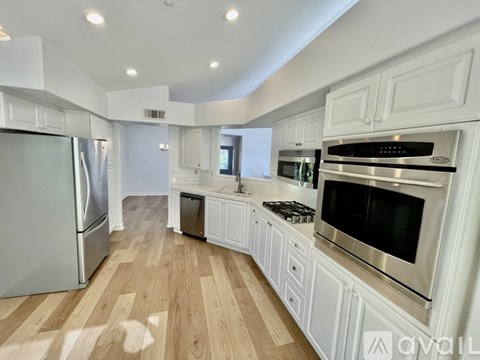 A modern kitchen with white cabinets and stainless steel appliances.