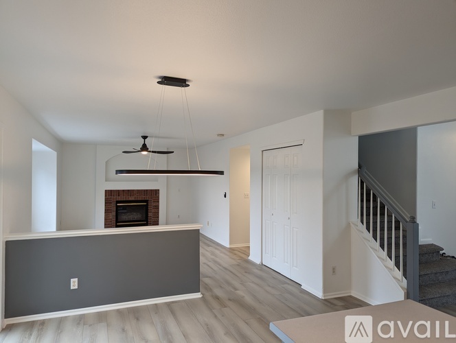 A spacious living room with a fireplace and a staircase.