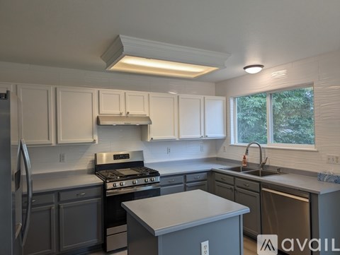 A kitchen with white cabinets and a stove top oven.