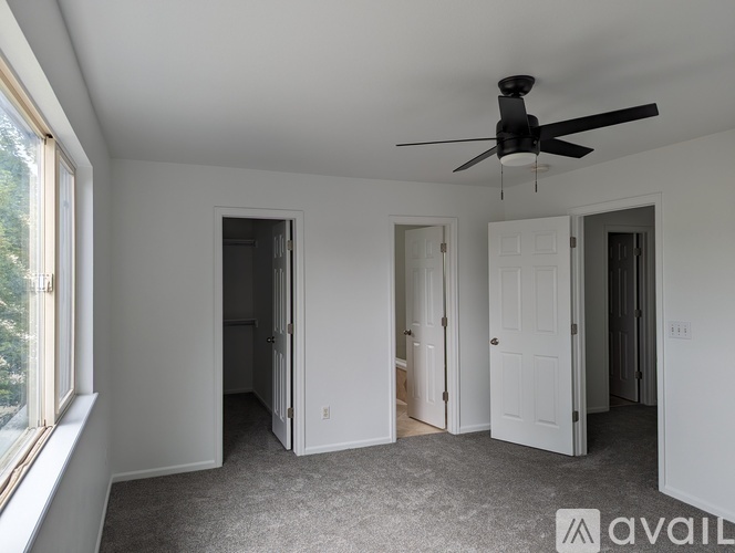 A spacious room with a ceiling fan and carpeted floor.