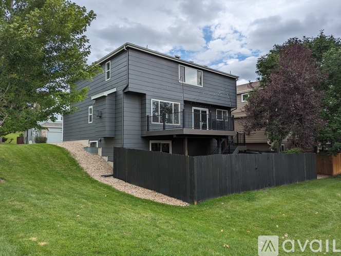 A modern house with a grey exterior and a black fence.