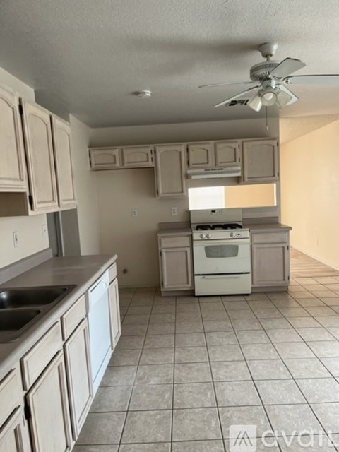 A kitchen with white cabinets and a fan on the ceiling.