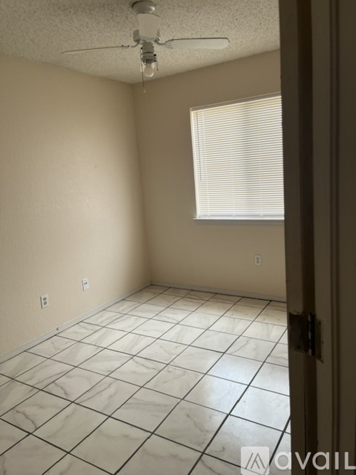A room with a ceiling fan and a window with blinds.