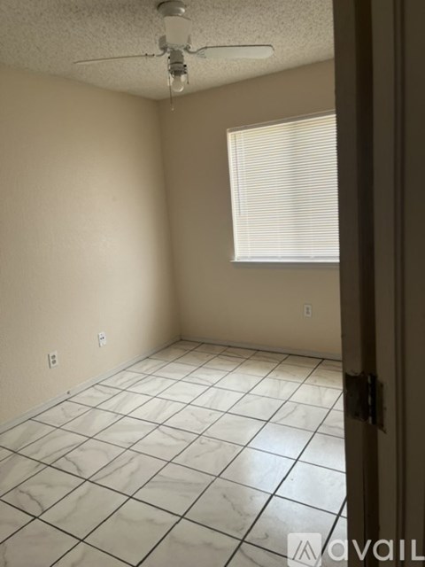 A room with a ceiling fan and a window with blinds.