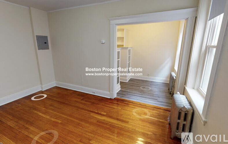 A room with wooden flooring and a window on the right side.