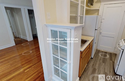 A kitchen area with a refrigerator, cabinets, and a countertop.