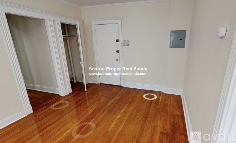 A room with wooden floors and white walls, with a door and a window.