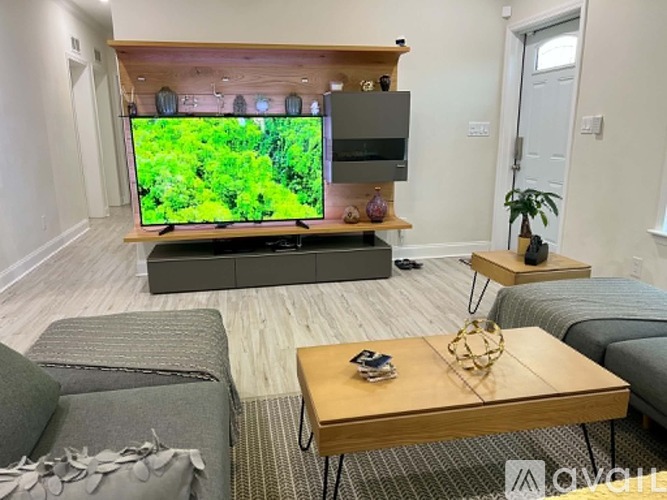 A living room with a grey couch, a wooden coffee table, and a television on a wooden stand.