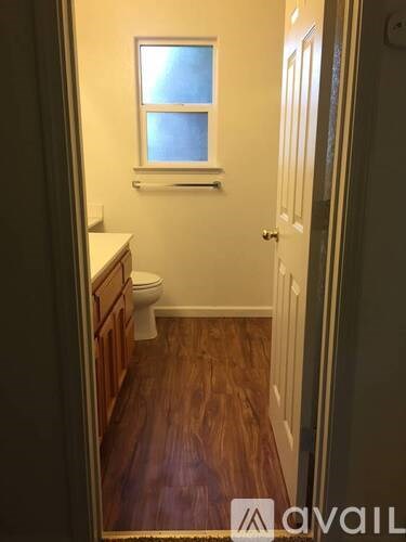 A small bathroom with wood floors and white walls.