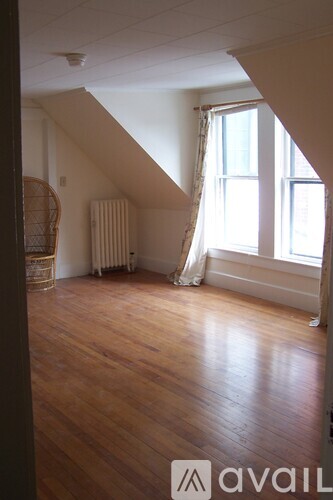 A room with wooden floors and a window with curtains.