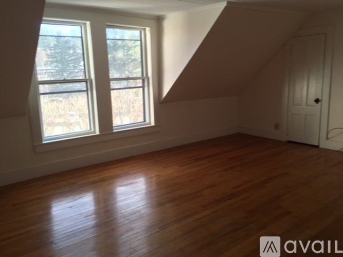A room with wooden floors and a window overlooking a field.