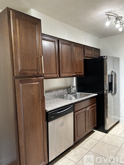 A kitchen with wooden cabinets and a black refrigerator.