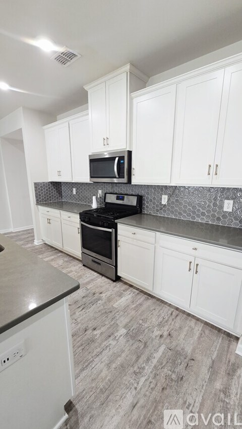 A kitchen with white cabinets and a black stove top oven.