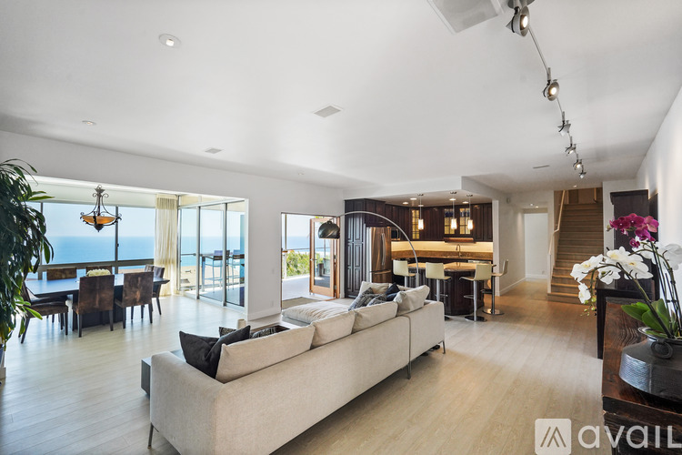 A spacious living room with a large couch and a view of the ocean.