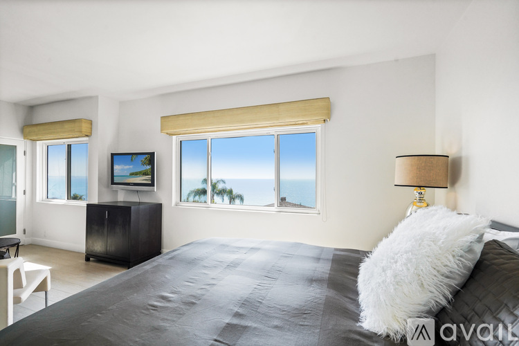 A bedroom with a large bed and a view of the ocean through the window.