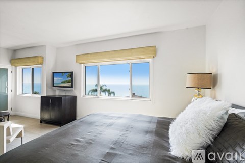 A bedroom with a large bed and a view of the ocean through the window.