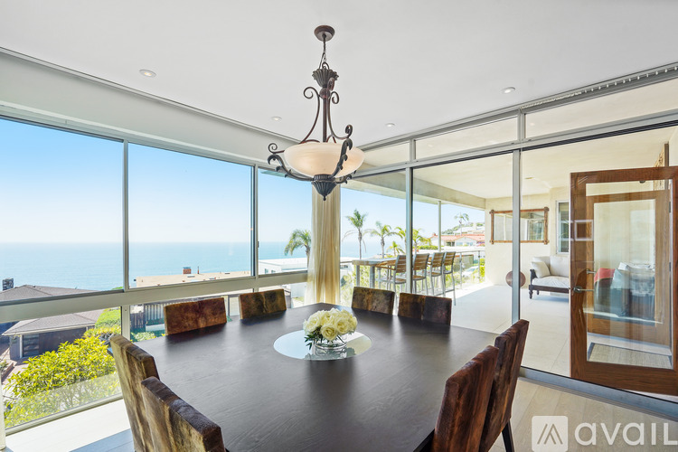 A dining room with a table set for two and a chandelier hanging from the ceiling.