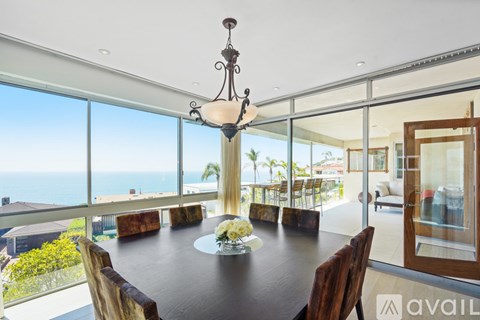 A dining room with a table set for two and a chandelier hanging from the ceiling.