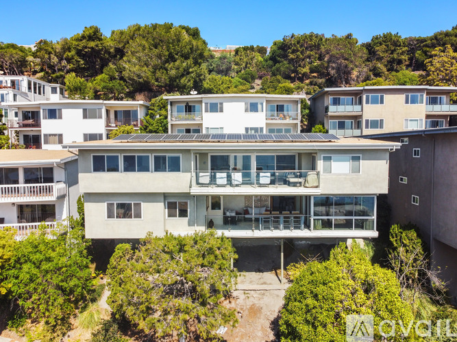 A row of houses with balconies and trees in the foreground.