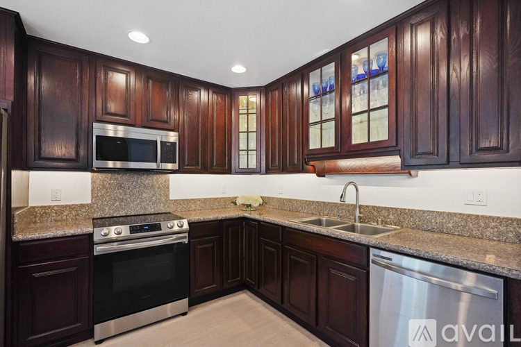 A kitchen with dark wood cabinets and stainless steel appliances.
