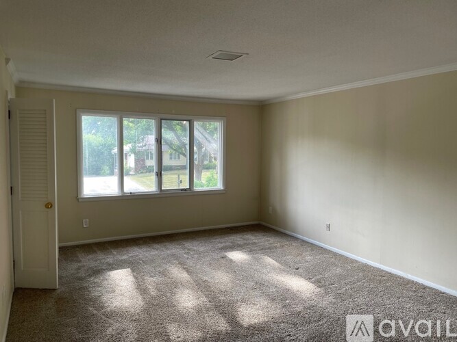 A room with a carpeted floor and a large window.