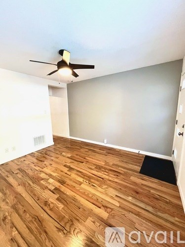 A room with wooden flooring and a ceiling fan.