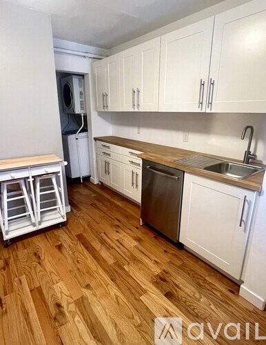 A kitchen with white cabinets and a wooden floor.