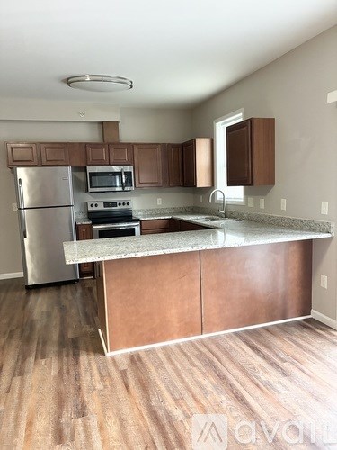 A kitchen with wooden cabinets and a stainless steel refrigerator.