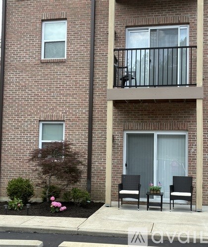 A brick building with a balcony and two chairs in front.