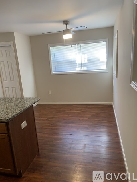 A room with a wooden floor and a window with blinds.