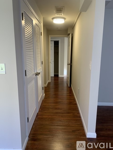 A long hallway with white walls and wood floors.