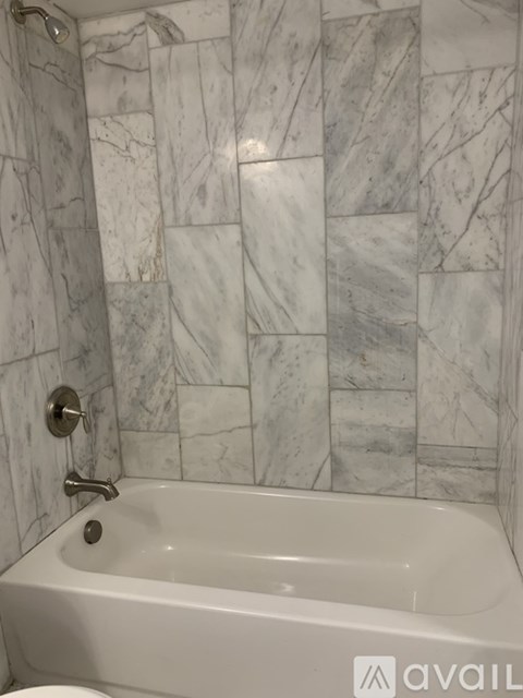 A white bathtub with a silver faucet and a shower head.