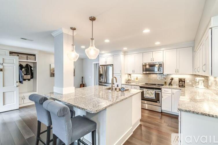A modern kitchen with granite countertops and white cabinets.
