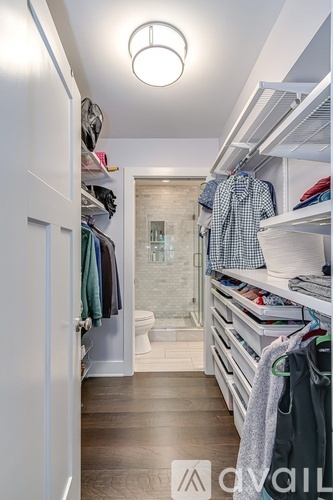 A walk-in closet with clothes hanging and drawers underneath.