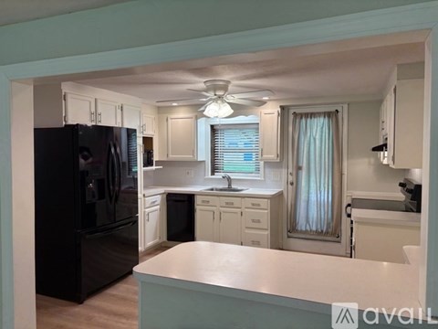 A kitchen with a black refrigerator and white cabinets.