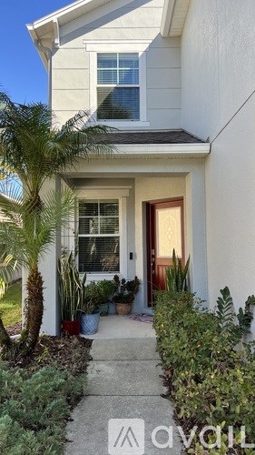 A white house with a brown door and a small garden in front.