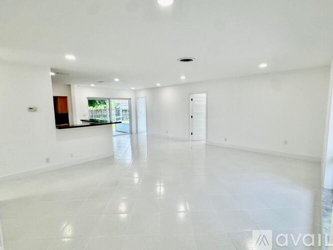 A spacious, empty room with white flooring and walls.