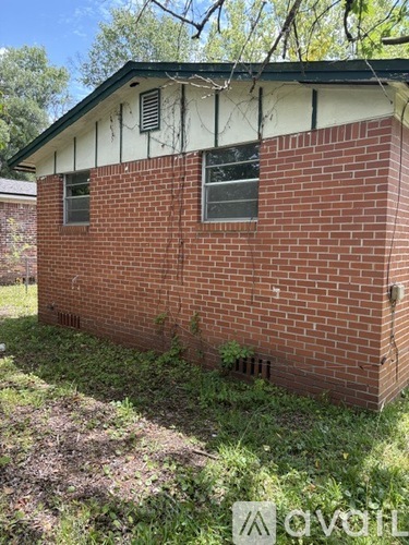 A small red brick house with a white roof and a window.