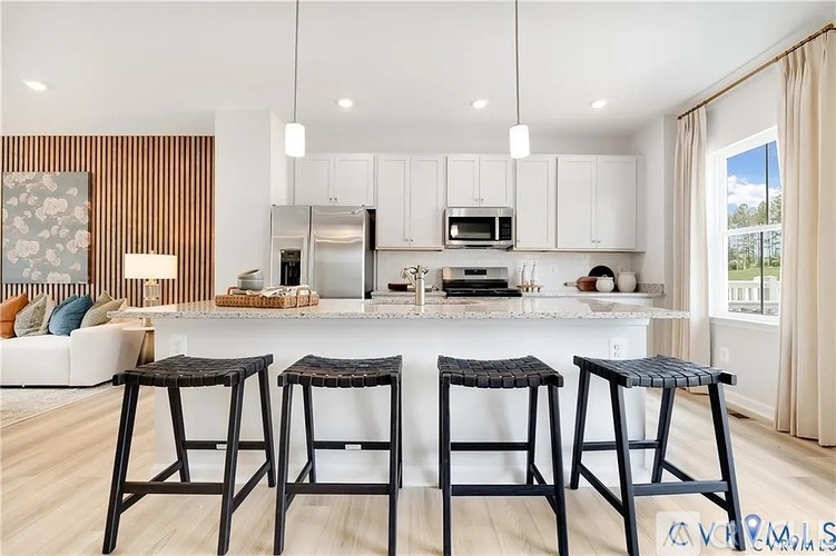 A kitchen with white cabinets and a bar area with two stools.