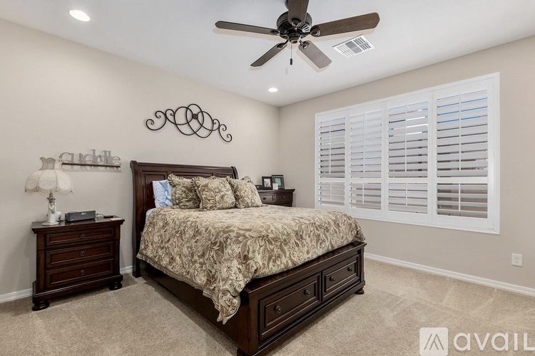 A bedroom with a large bed, a ceiling fan, and a nightstand with a lamp.