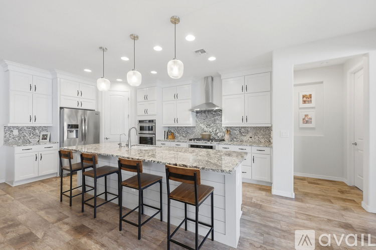 A kitchen with white cabinets and a marble countertop.