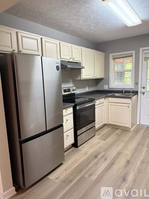 A kitchen with a stainless steel refrigerator and wooden floors.