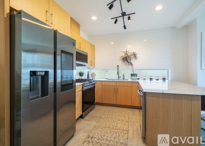 A modern kitchen with a refrigerator, microwave, and oven.