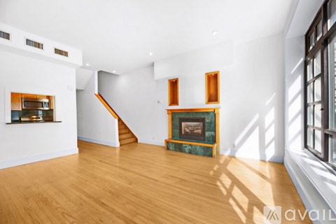 A spacious room with wooden floors and a staircase.
