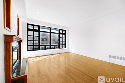 A room with wooden floors and a large window with a view of a cityscape.