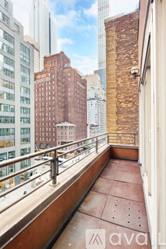 A balcony with a metal railing and a brick wall.