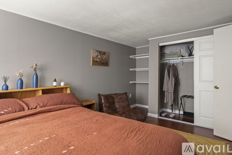 A bedroom with a bed, a chair, and a shelf with decorative items.