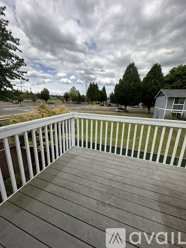 A deck with a railing and a view of a grassy area and trees.